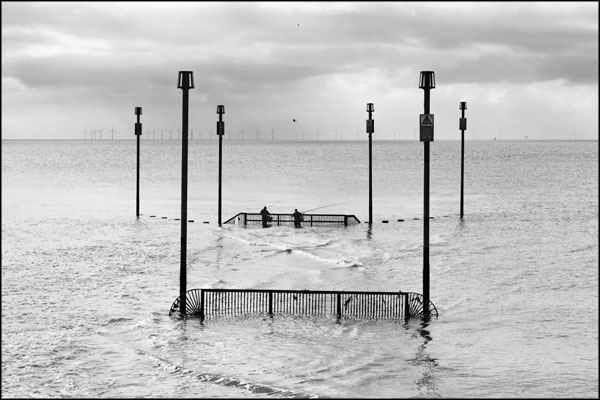 B-066. Fishing at the Southwick outfall, as rain falls upon the wind farm - by Greig Clifford